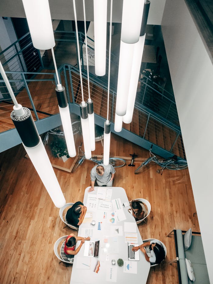 High angle shot of team collaborating at a stylish desk with ceiling lights in a modern office.